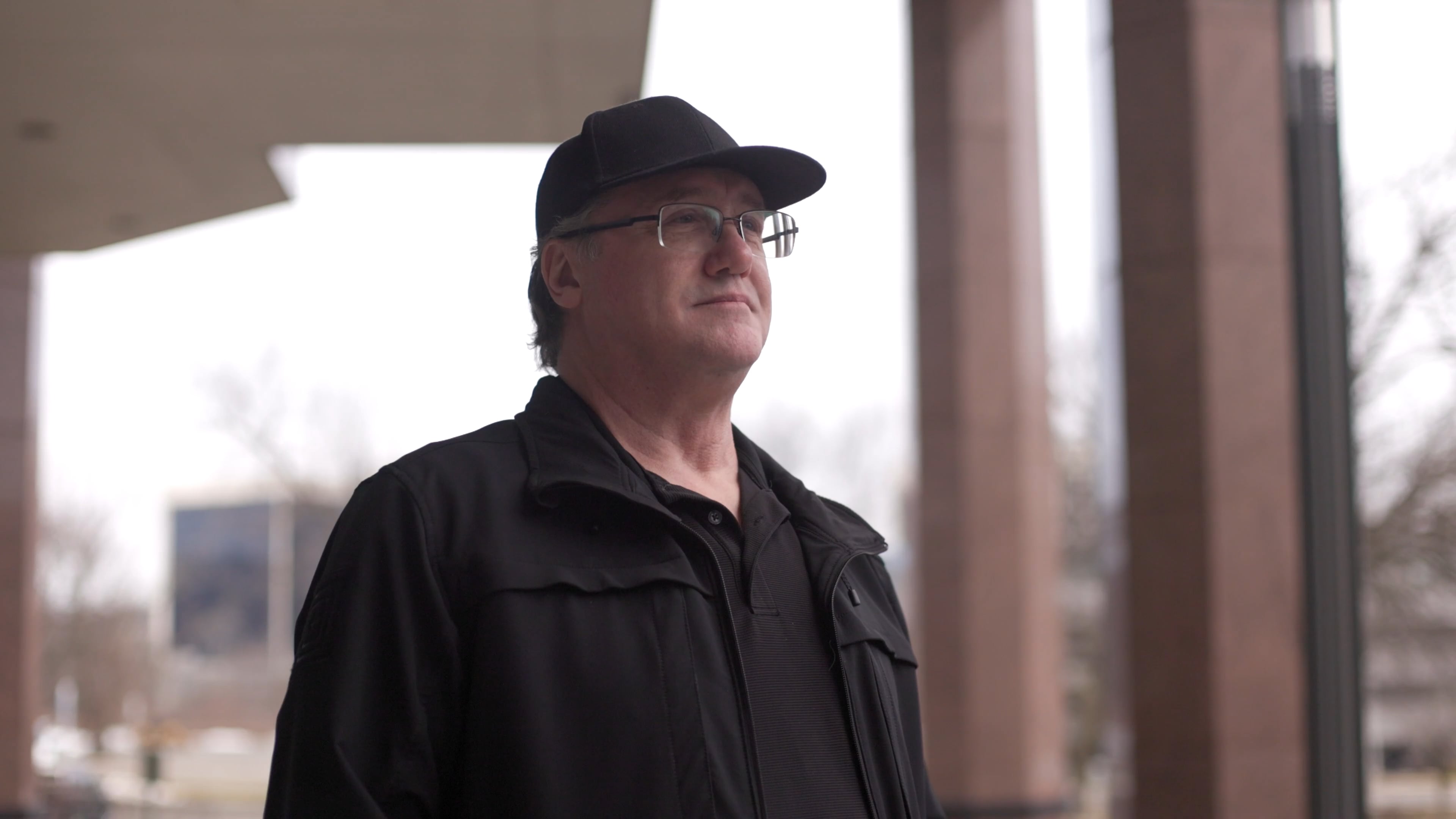 Man in a baseball cap and glasses looking up and to the right
