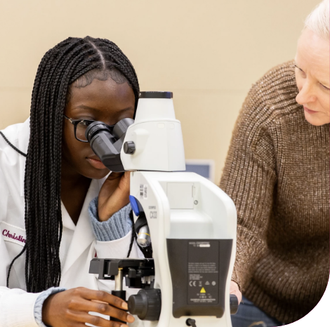 Scientist Using Microscope with Colleague Observing