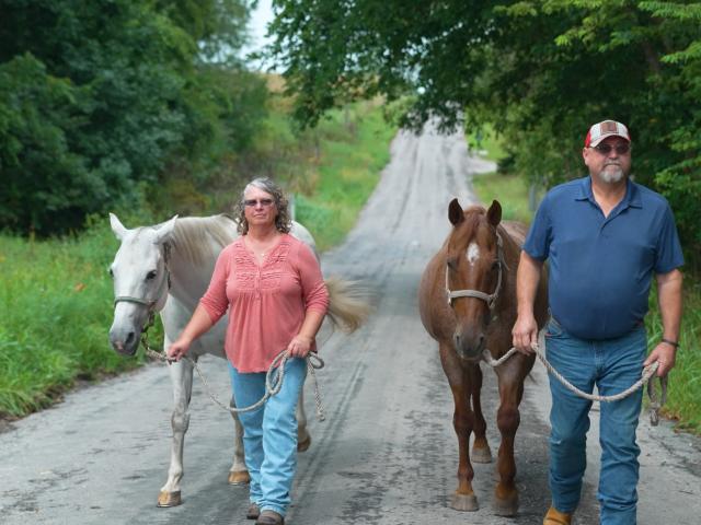 Rick and his wife Kim walking horses down a rural road