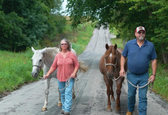 Rick and his wife Kim walking horses down a rural road