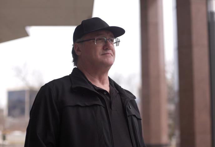 Man in a baseball cap and glasses looking up and to the right