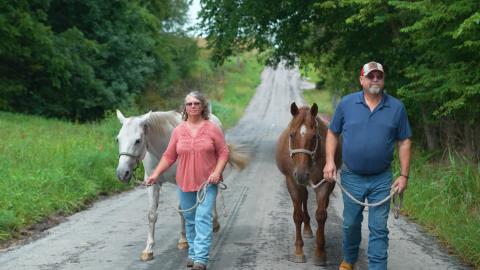Rick and his wife Kim walking horses down a rural road