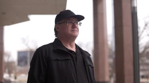 Man in a baseball cap and glasses looking up and to the right