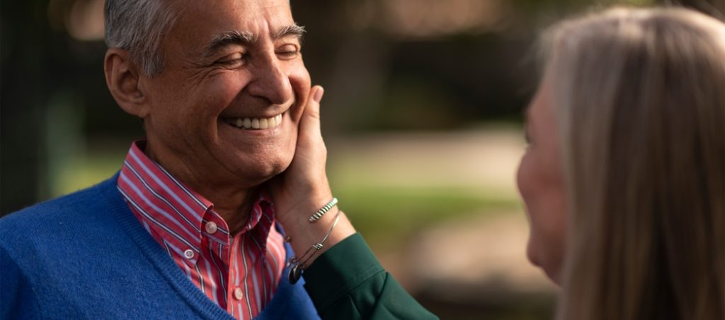 Older woman holding man's cheek while he smiles at her